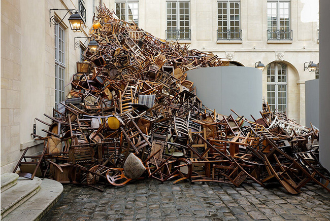 Tadashi kawamata`s tumbling avalanche of wooden chairs sweeps through paris courtyard